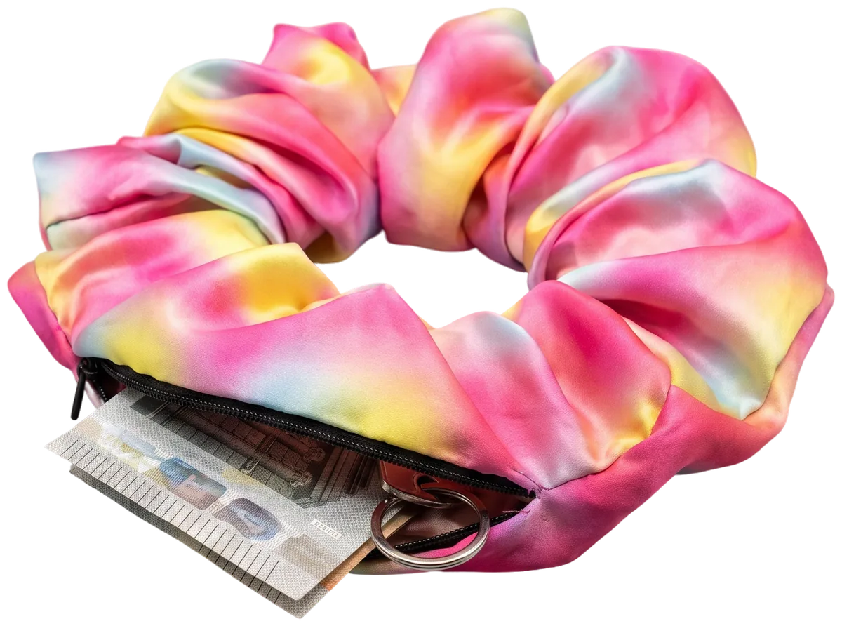 Das Gradient-Scrunchie mit geöffnetem Reißverschlussfach, aus dem ein gefalteter Geldschein und ein Schlüsselring herausschauen.
