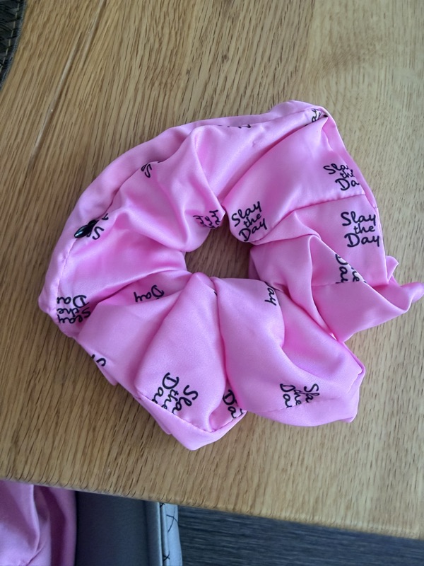 Close-up of the pink scrunchie showing the lettering pattern